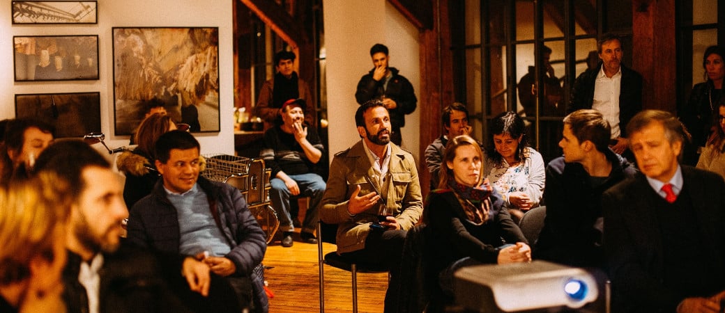 Group discussion in a casual indoor setting with participants seated in a circle, with a projector visible in the foreground